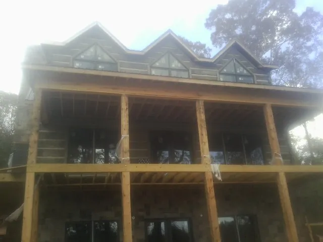 Dormers and porch framing on a large log home under construction — Roof Coating work by our crew in Midlothian
