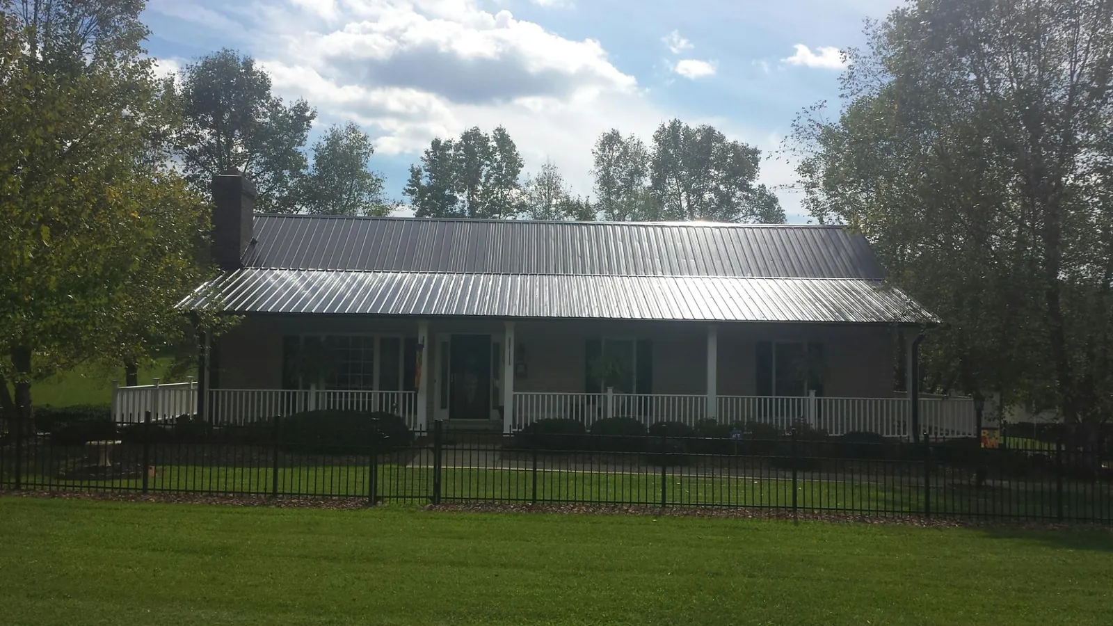 Gray metal roof on a brick ranch with a full width front porch — Gutter Guard Installation work by our crew in Midlothian