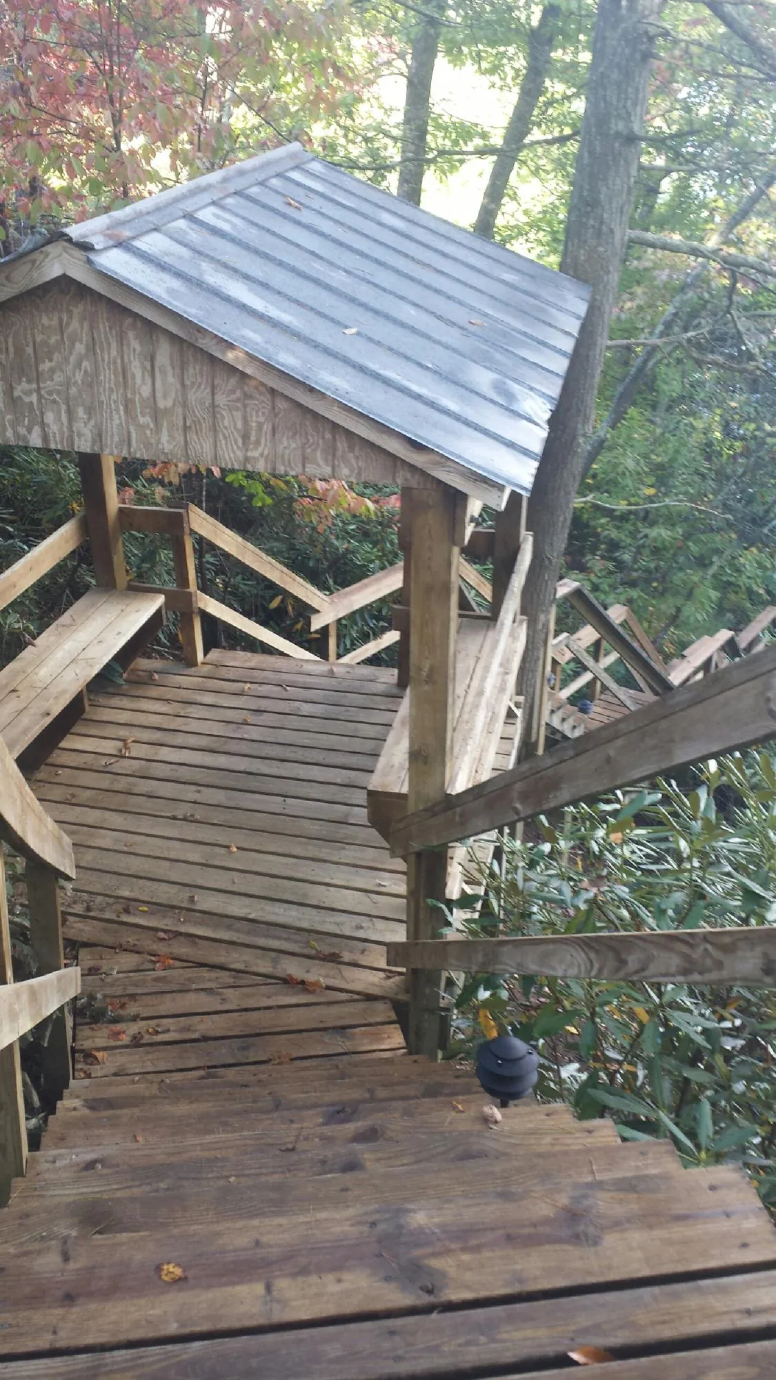 Metal roofed shelter over wooden steps on a wooded walkway — Skylight Repair & Installation work by our crew in Midlothian